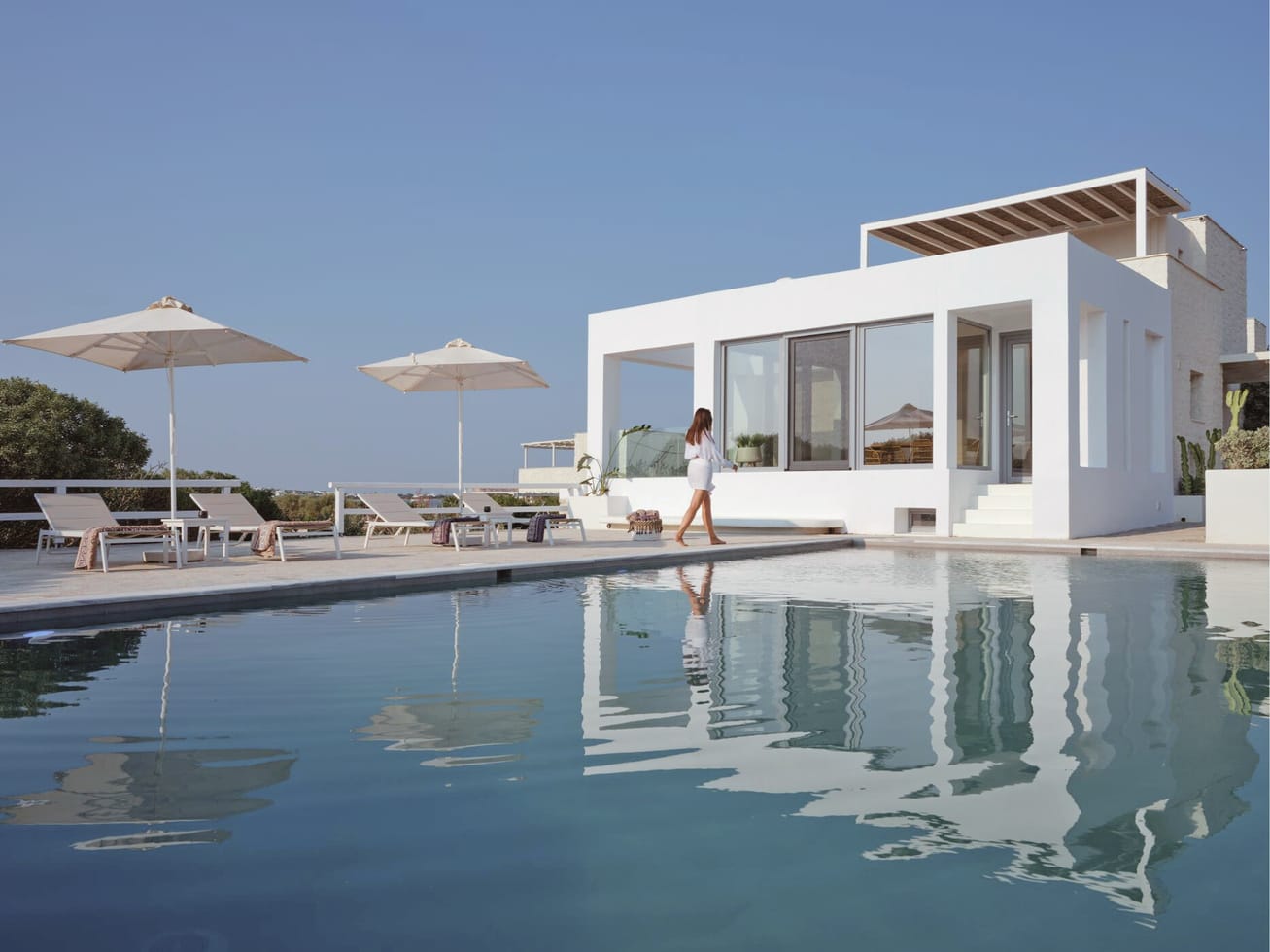 Grand Ambassador Villa seen across its pool, white cubic volumes with sun umbrellas